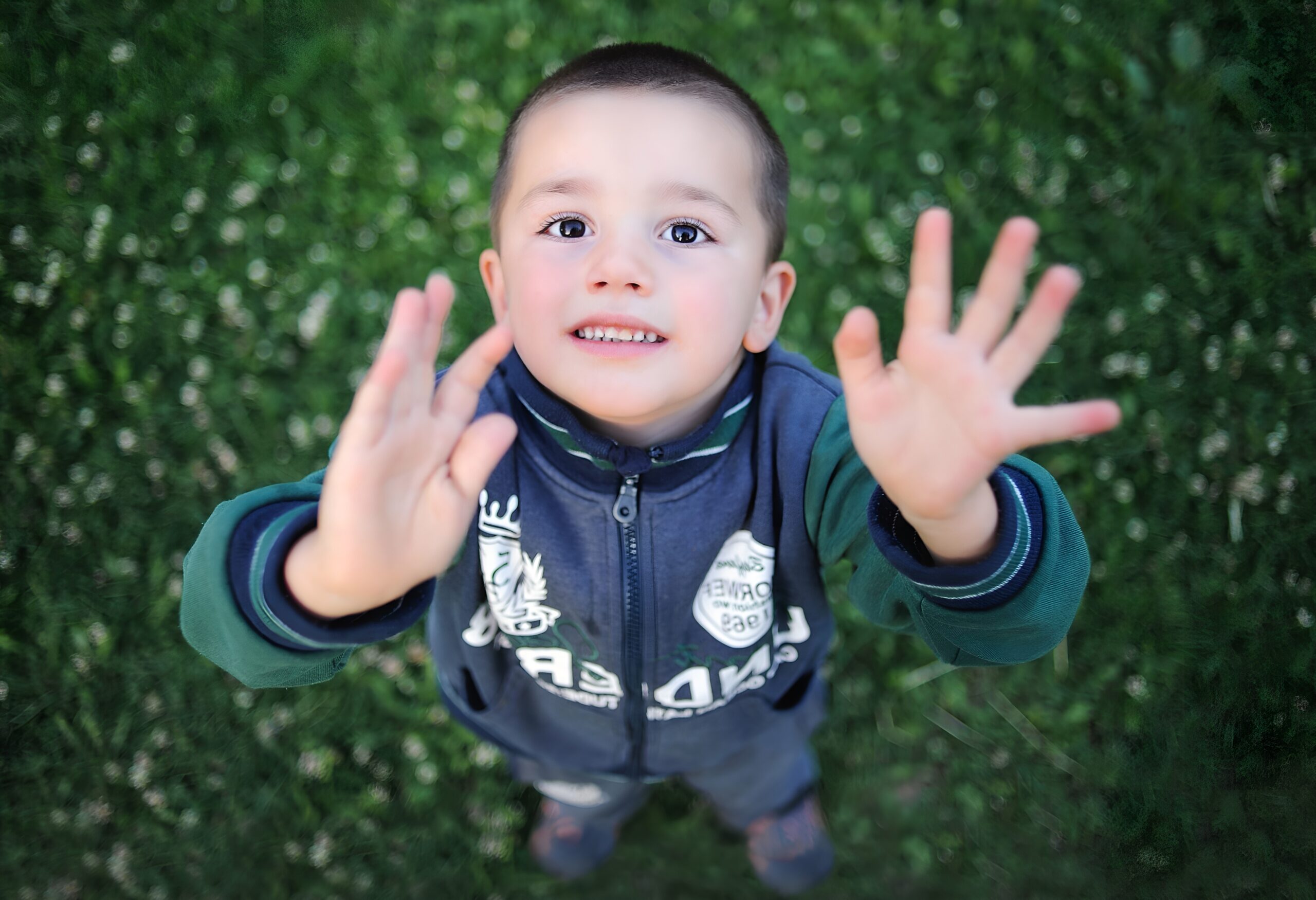 Niño mirando hacia arriba con las palmas de las manos a cámara